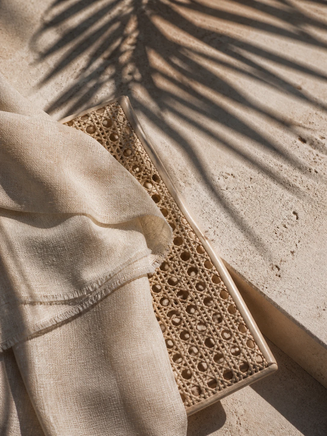 Natural fabric and woven cane crossed by palm shadows